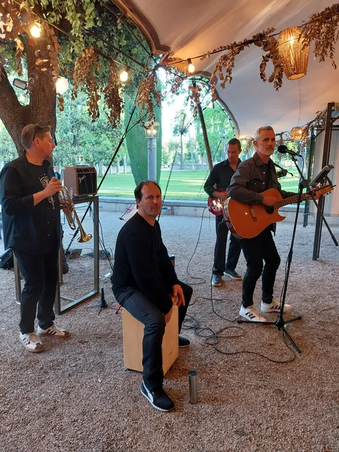Formato acústico bajo un árbol, con cajón, guitarra y trompeta.