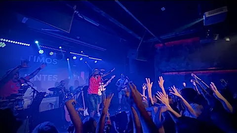 La sala bañada en azul, con los brazos del público en alto.