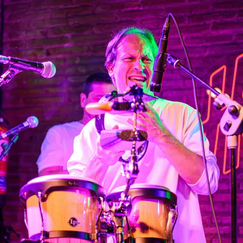 Manu toca las congas y canta al micrófono.
