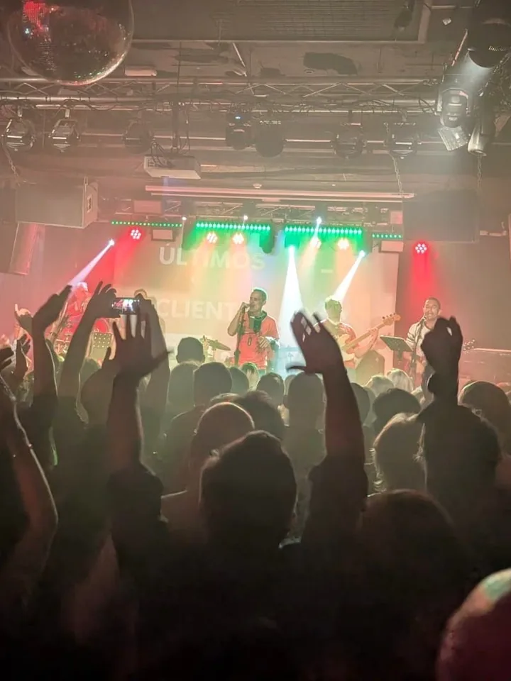 La Sala Moby Dick llena, vista desde el fondo: brazos en alto por toda la pista y Últimos Clientes en el escenario, con su nombre en el muro de luz.