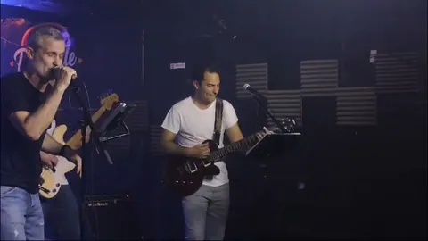 Cantante y guitarra solista en el escenario de un club, luz azul.