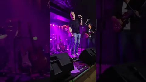 Cantante y bajista en la sala Rockville de Madrid, luz malva.