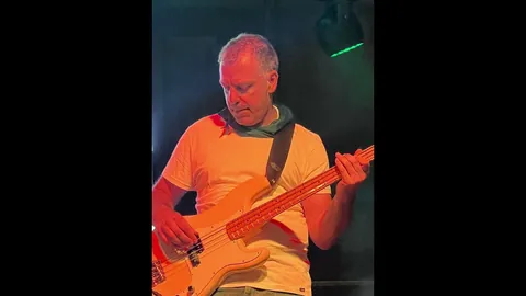 El bajista tocando bajo luz naranja en la Féria de Céret.